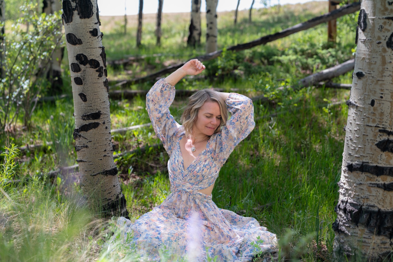 Nicole Marie Rose with arms raised among aspen trees